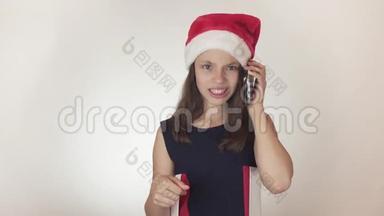 戴着圣诞老人帽子的漂亮顽皮少女在白色背景下的智能手机上进行情感交流